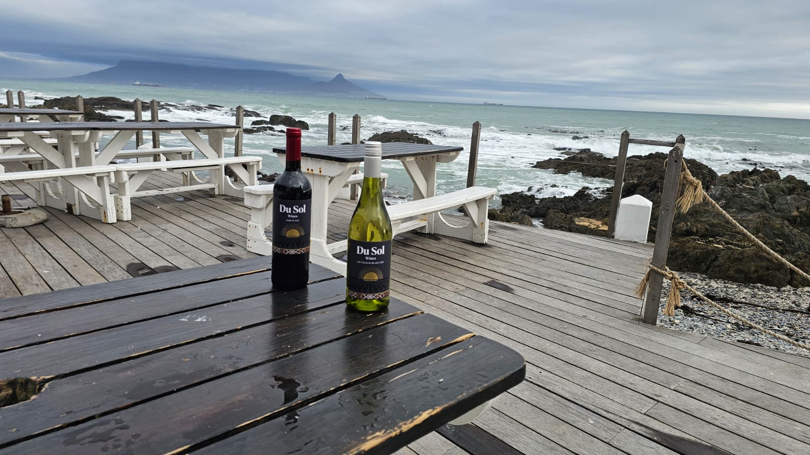Du Sol red and white on a weathered deck table by the Cape coast