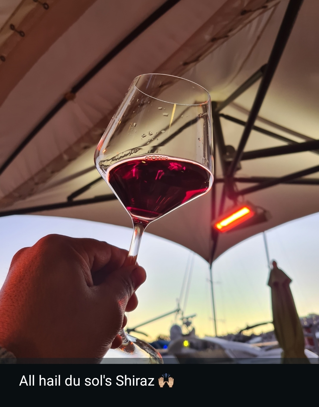 A glass of Du Sol Shiraz raised against the sunset