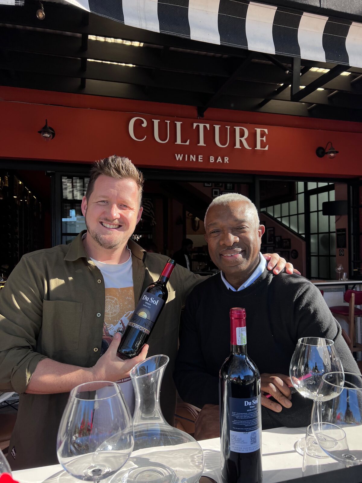 Two friends toasting Du Sol Shiraz and Merlot outside Culture Wine Bar
