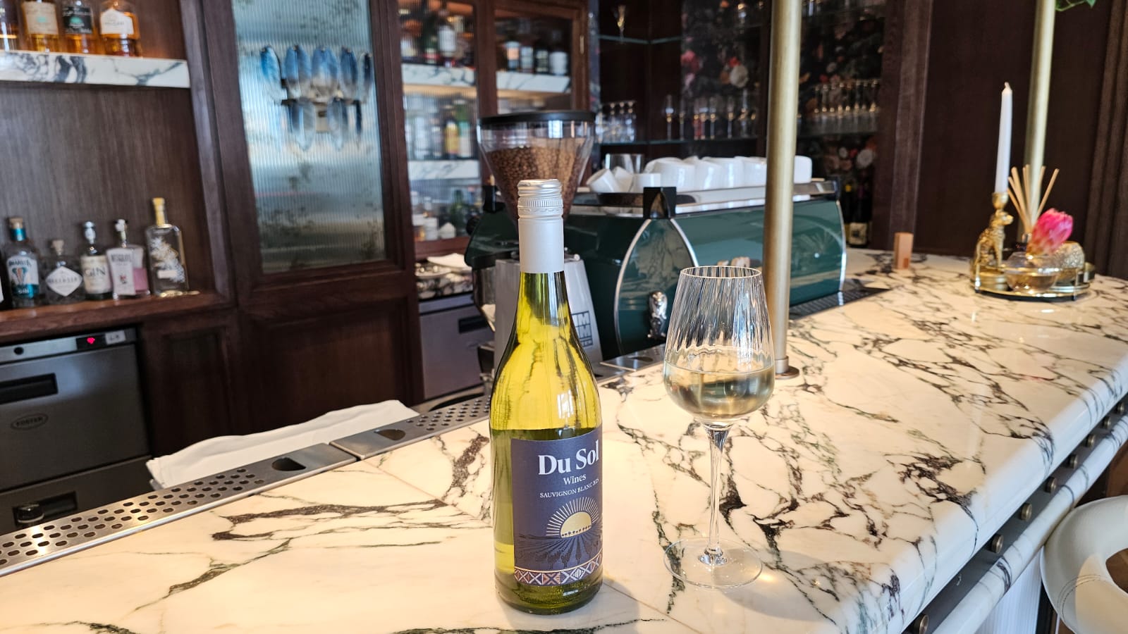 Du Sol Sauvignon Blanc and a glass of white on an elegant marble bar